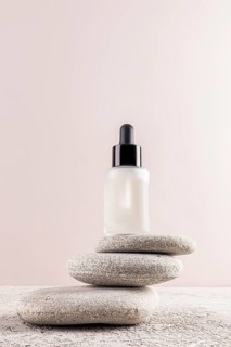 A minimalist image featuring a serum bottle with a black dropper, elegantly balanced on smooth