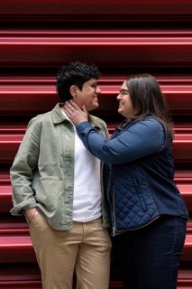 A joyous moment captured between a curvy lesbian couple standing closely outdoors. They gaze