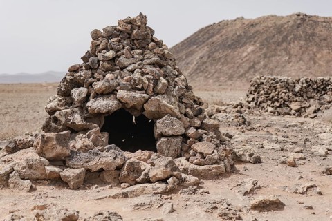 Traditional stone hut amidst a dry, barren landscape in Fuerteventura, exemplifying the arid