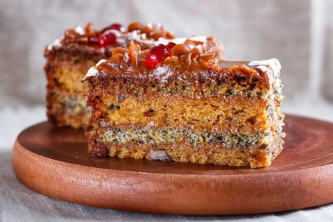A piece of cake with caramel cream and poppy seeds on a wooden kitchen board. close up, selective