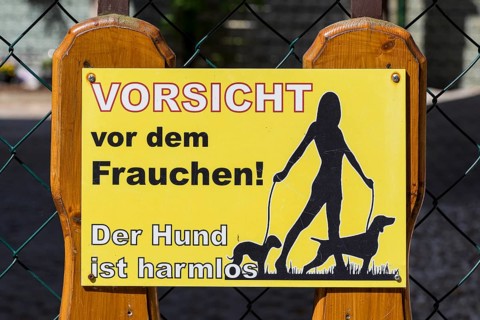 Funny sign on a fence, beware of the mistress, the dog is harmless