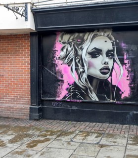 Street art mural of young woman Phantom Trace on shop wall, Colchester, Essex, England, UK by