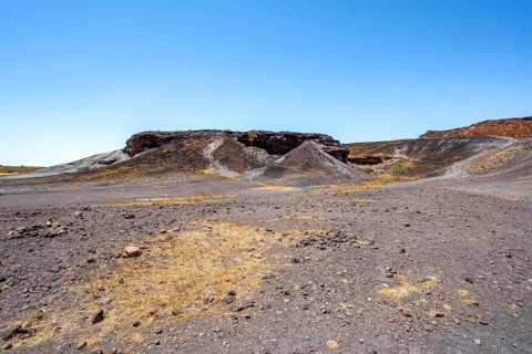 Dry landscape with yellow grass and black volcanic hills, Burnt Mountain, Damaraland, Kunene,