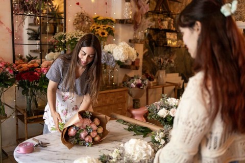 A woman skillfully arrange floral bouquets in a cozy florist shop. Surrounded by a variety of