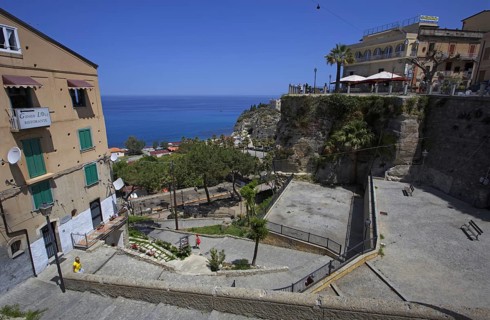 Elevated view of the old town with stairs and terrace and view of the endless blue sea, Tropea,