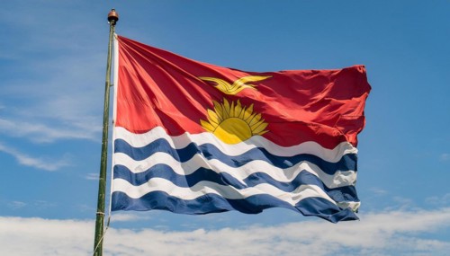 The flag of Kiribati, Polynesia, flutters in the wind, isolated against a blue sky