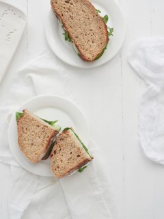 Veggie sandwiches served on plates on a white wooden table with space for text