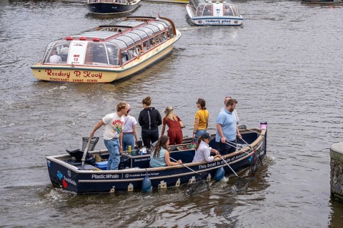 Plastic Whale boat in a canal in Amsterdam, passengers fish plastic waste out of the canals, tour