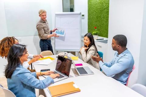 Business team analyzing positive data charts during a presentation in a modern coworking office