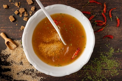 Broth with quinoa, parsley and red hot peppers in a bowl, surrounded by ingredients