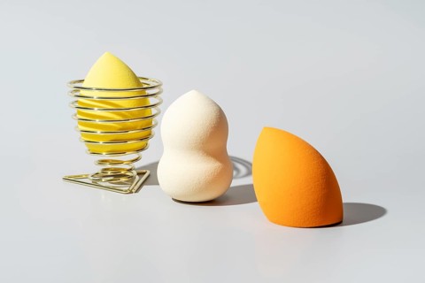 A collection of cosmetic sponges in diverse shapes and vibrant colors, including yellow in a