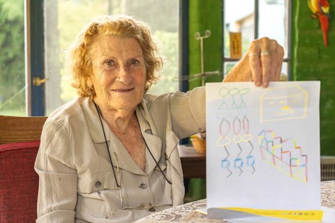 Happy grandmother proudly displaying a colorful drawing made by her grandchild, enjoying a