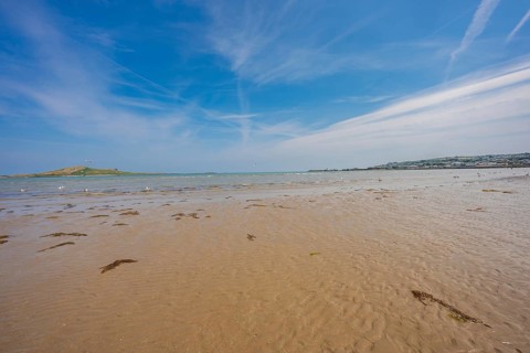 Wide beach landscape with sea view and cloudy sky, low tide, Howth beach, Ireland