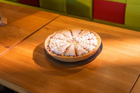 A fruity cake with cream presented on a wooden table, Café Kuh, Deckenpfronn, Germany