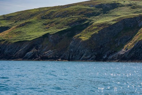 Green hills rise above sparkling blue coastal waters, cliff tour, Howth, Ireland