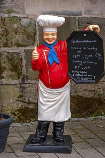 Cooking figure with menu in front of an inn, Altdorf, Middle Franconia, Bavaria, Germany