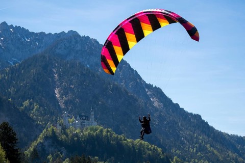 Skydiver flying against a picturesque mountain backdrop with castle, Neuschwanstein Castle,