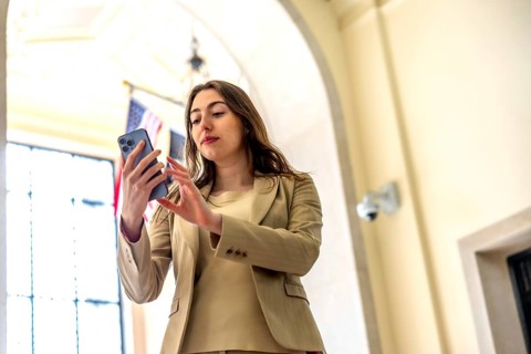 Young professional woman in formal wear interacting with her smartphone, checking messages or
