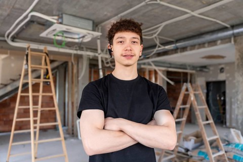 Young man working as an hvac technician standing confidently with crossed arms, smiling at a