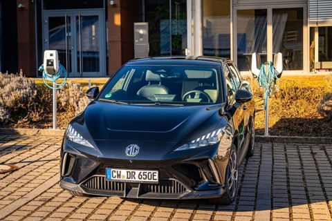 Black vehicle in front of a building with charging stations, Deer E- Carsharing vehicle MG4,