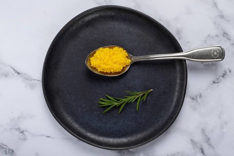 Pearl yuzu, yuzu caviar - pearl, on a spoon, top view, on a dark gray plate, there are no people.