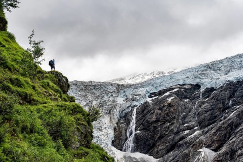 Mountaineer on a rock, cloudy mountain landscape with Grindelwald-Fiescherfirn glacier, Bernese
