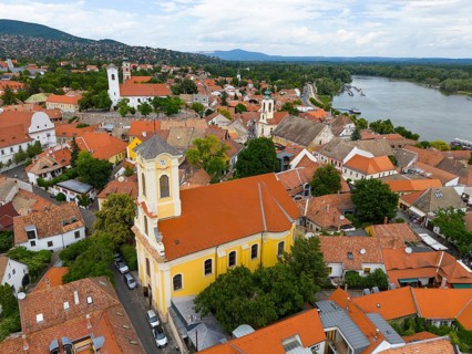 Cityscape with a centrally placed church surrounded by red roofs and a river nearby, aerial view,