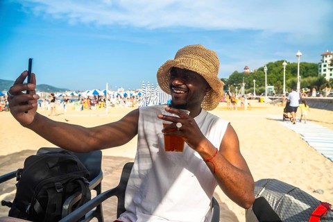 Smiling young man enjoying a relaxing summer vacation, holding a refreshing drink and taking a