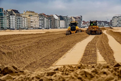 Bulldozers when distributing sand on the beach in the town of Knokke-Heist, part of coastal