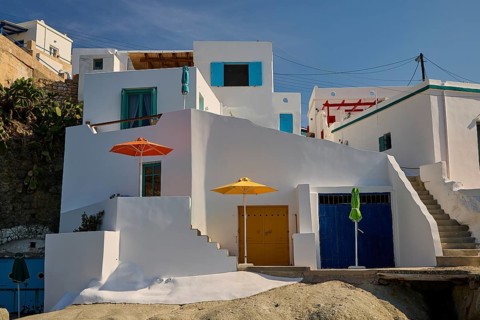 Whitewashed buildings with colored doors and umbrellas, under blue skies in Mediterranean
