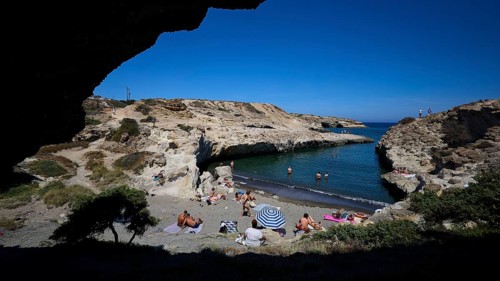 People relaxing on the beach in a rocky bay in the shade with a view of the open sea, Kapras,