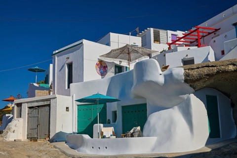 White Mediterranean houses with green decoration built into rocks, Syrmata, boat garages,
