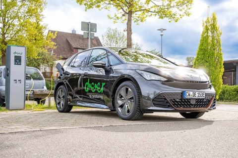 Electric vehicle at a charging station in an urban environment under cloudy skies, Deer Charging