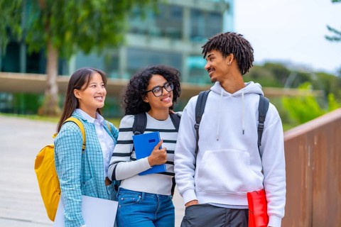 Three quarter length photo of three cool diverse students talking standing together outside the