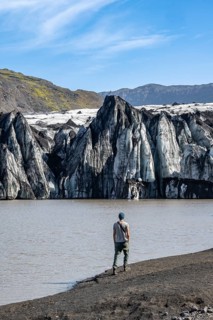 Tourist at the lakeside of a glacier lagoon, glacier tongue with crevasses and lake,