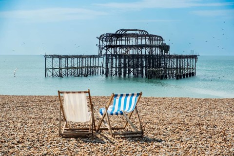 Two folding chairs on the beach in front of the ruins of the burnt down West Pier in Brighton, East