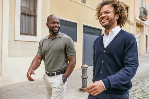 Two coworkers walking and talking in a sunny Barcelona street, enjoying a casual meeting outside