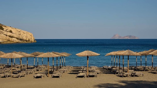 Paximadia island, quiet beach with umbrellas and deckchairs, view of a distant island, Matala,