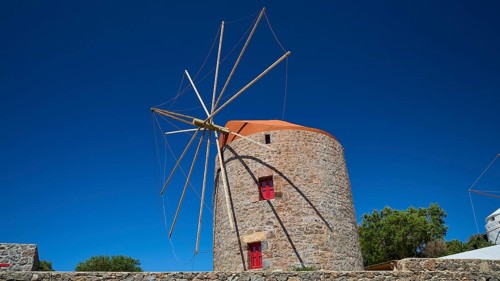 Stone windmill with blue roof and red window under clear blue sky, Trypiti, Tripiti, village,