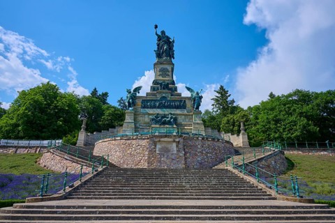 Monumental statue on stepped landscape, framed by trees and sky, Niederwalddenkmal, Rhine,