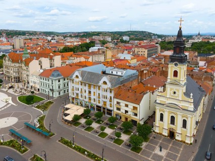 Church tower dominates an old town with red tiled roofs and urban architecture, aerial view, center