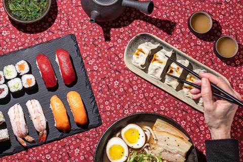 Artistic composition of a traditional Japanese feast, including sushi, dumplings, and ramen, with a