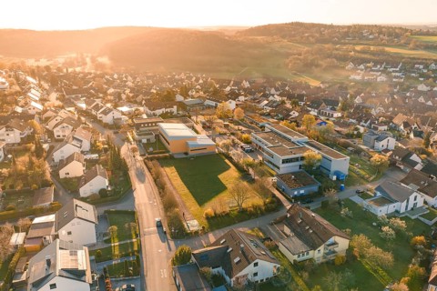 Urban suburbs seen from the air with buildings and roads at sunset, Schlehengäuschule, Gechingen,