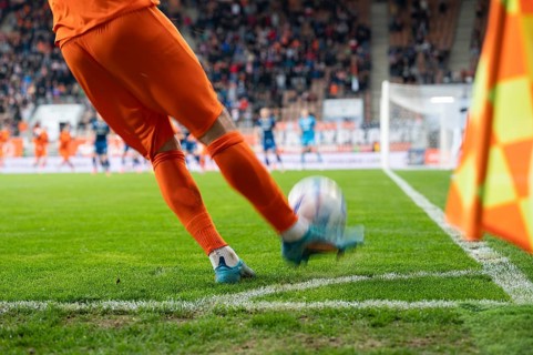 Footballer takes the corner. Detail of player's legs and the ball during soccer match in Lubin,