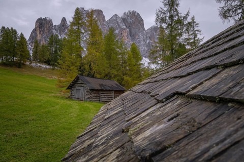 View over a wooden roof of a mountain hut to a part of the Geisler group from the Gampenwiese,
