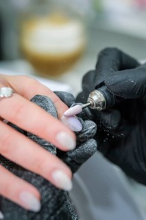 Precision manicure image of a rotating nail drill shaping the surface of a long almond nail while