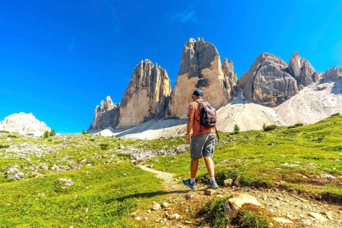 Tourist enjoying a scenic hike on the tre cime di lavaredo trail amidst the breathtaking peaks of