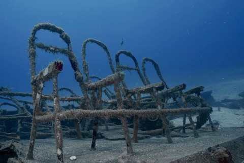 Dark underwater view of rusted ferry benches at the bottom of the sea, meteor wreck dive site,