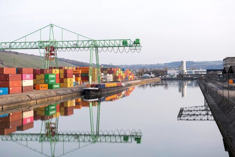 A crane stands in a port full of containers that are reflected in the water, Stuttgart,