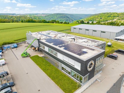 Modern office building with solar roof, embedded in a green landscape, PV assembly, Perrot company,